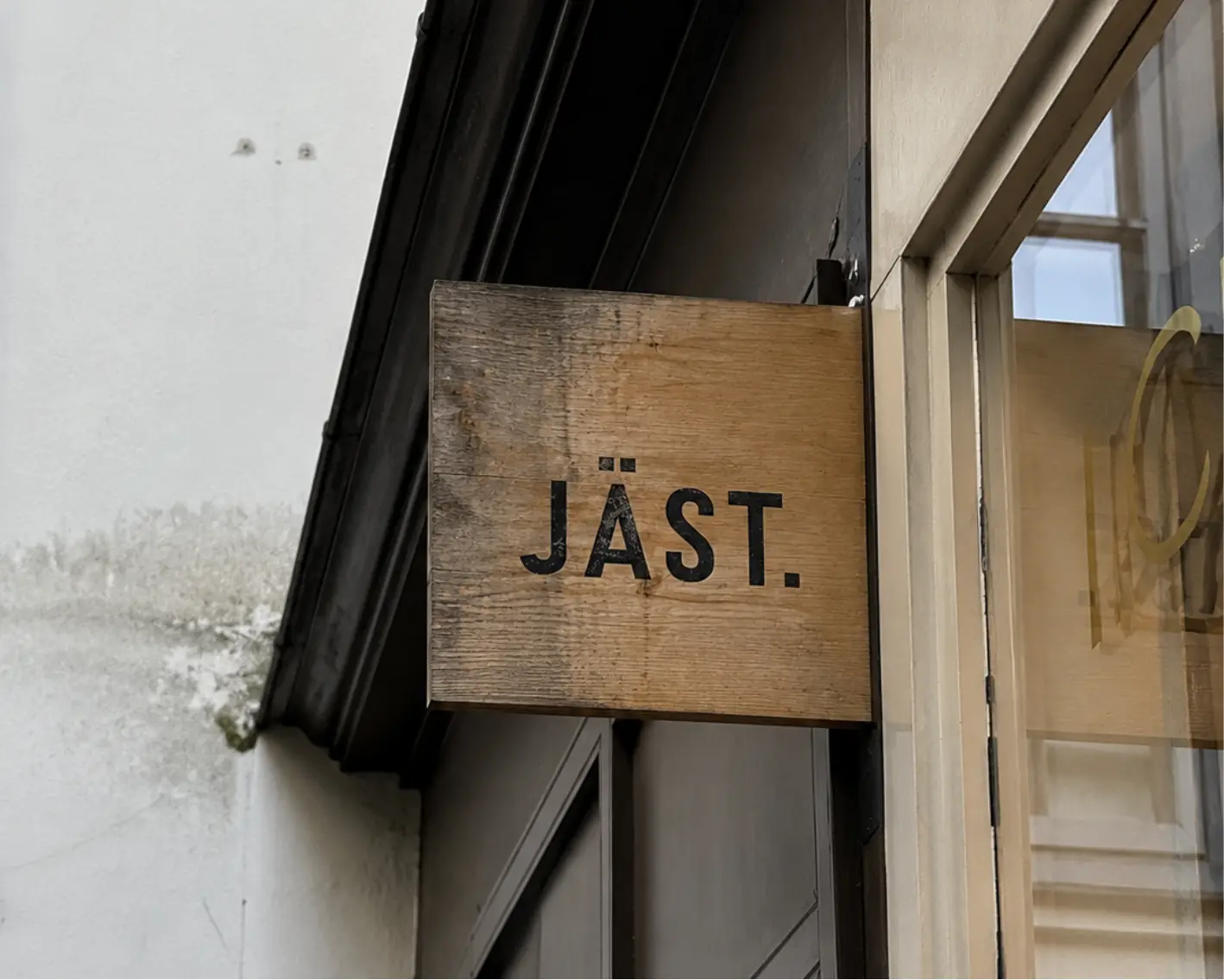 JÄST. visual concept: a simple wooden projecting sign on a plaster facade